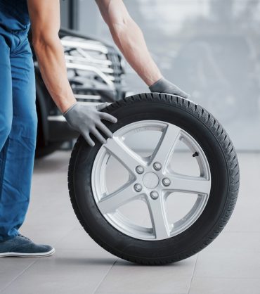 Mechanic holding a tire tire at the repair garage. replacement of winter and summer tires.